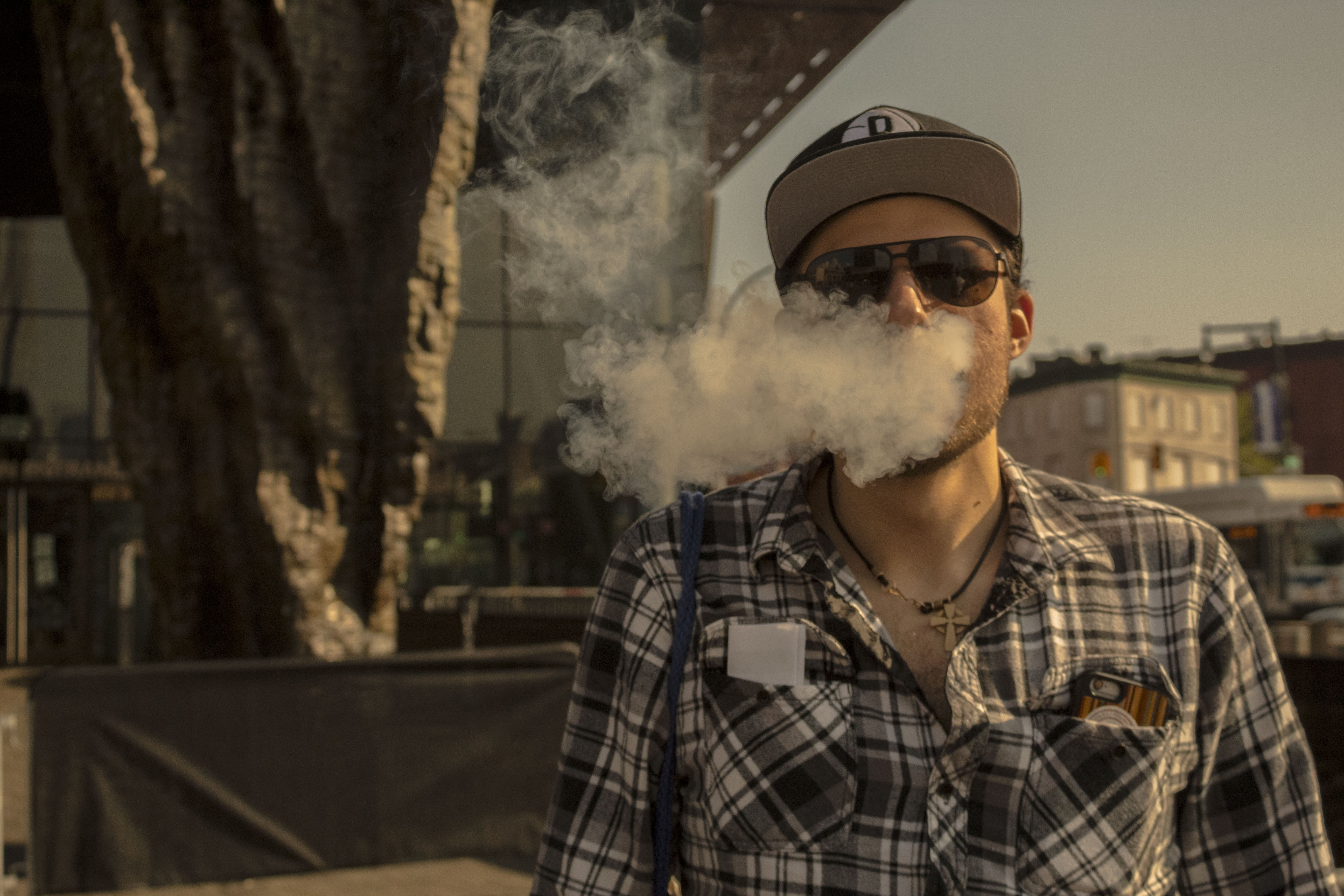 man releasing a smoke cloud while wearing sunglasses
